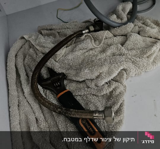 מפתח צינורות וצינור גמיש על מגבת